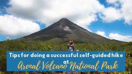 Arenal Volcano towering over lush green rainforest under a partly cloudy sky in Costa Rica